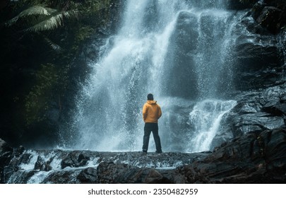 Man standing on a rock with huge waterfall on the background, Kerala travel photography shot from Kappimala Kannur - Powered by Shutterstock