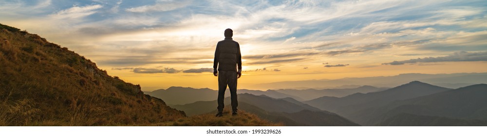 The man standing on the rock with a picturesque sunset
