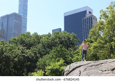 Man standing on rock while standing in front of city scape 