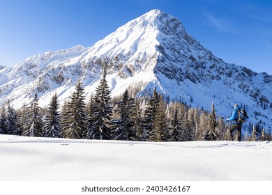 Man standing on snow field with scenic view on snow capped mountain peak of Mittagskogel (Kepa) in Karawanks, Carinthia, Austria. Winter wonderland in Austrian Alps. Snowshoe hiking snowy landscape - Powered by Shutterstock