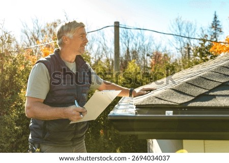 A man standing on steps inspecting house roof