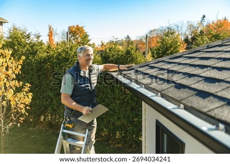 A man standing on steps inspecting house roof