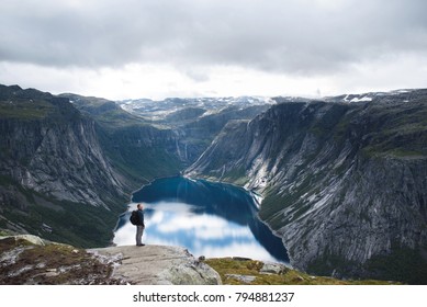 man standing on stone with view on lake