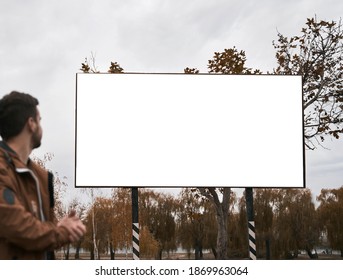 man standing on the street and looking on billboard. silhouette of man and blank poster. outdoor lifestyle advertisement mockup