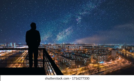 The man standing on the top of building on the starry cityscape background