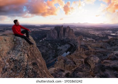 Man standing on top of a mountain is enjoying a beautiful landscape. Clolorful Sunset Sky Art Render. Taken at Smith Rock, Oregon, North America.