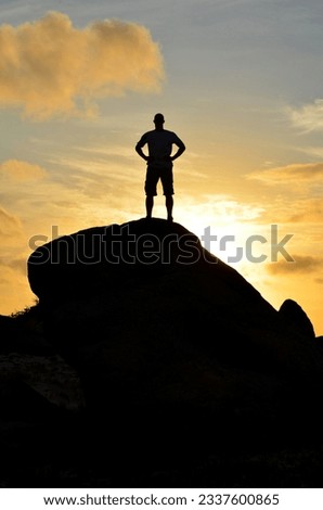 Man standing on top of a roack at sunrise in Aruba.