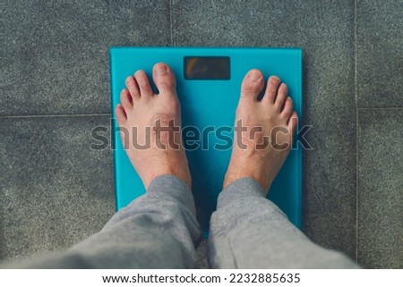 Man standing on weight scale. Male feet on glass scales, men's diet, body weight, close up, man stepping up on scales, side view