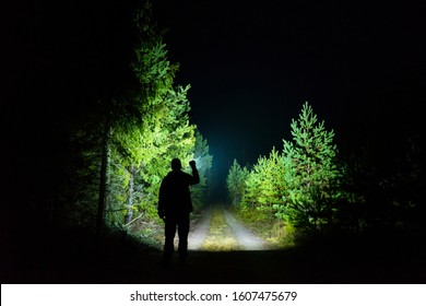 Man standing outdoor at rainy foggy night shining with flashlight. Mystical and abstract photo of Swedish nature and landscape.