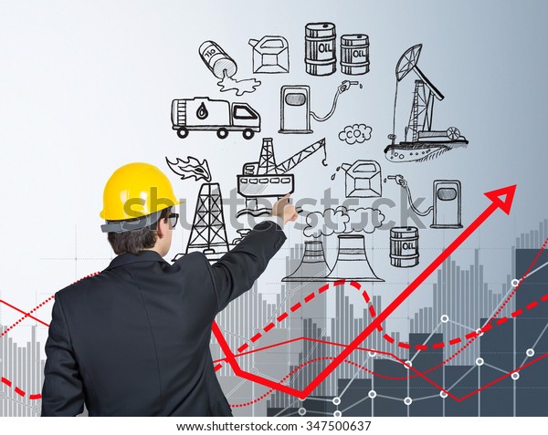 man standing and\
pointing at the illustration of oil production components on white\
wall,  back view, red graph of oil pollution, concept of\
environmental pollution