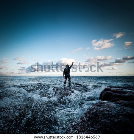 Man standing at sea shore facing incoming storm and waves