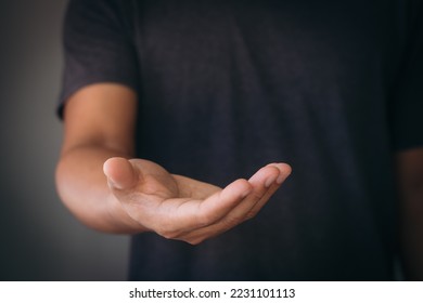 The man is standing and shows an outstretched hand with an open palm. Businessman showing empty hand and presenting with hand empty copy space. Open hand, Holding, giving, showing, presenting concept. - Shutterstock ID 2231101113
