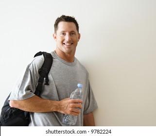 Man Standing Smiling With Gym Bag And Bottled Water.