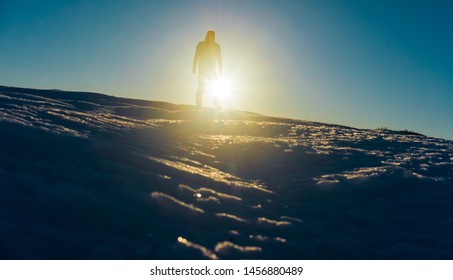 Man standing in snowscape at sunset