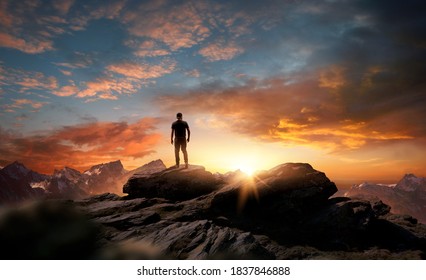 A man standing at the top of a mountain as the sun begins to set. Goals, hopes and aspirations concept. Photo compostion. - Powered by Shutterstock