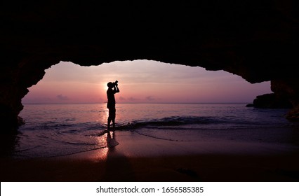 Man standing using camera To take a picture in front of the cave in the morning at sunrise
