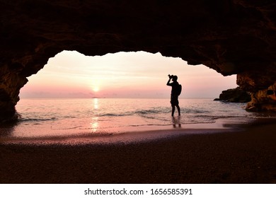 Man standing using camera To take a picture in front of the cave in the morning at sunrise