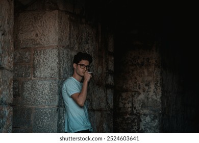 A man stands against a stone wall in a castle, casually smoking a cigarette in a quiet, dimly lit setting. The atmosphere is moody, with the old, rustic castle backdrop adding character to the scene. - Powered by Shutterstock