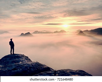 Man Stands Alone On The Peak Of Rock. Hiker Watching To Autumn  Sun At Horizon . Beautiful Moment The Miracle Of Nature. Colorful Mist In Valley. Man Hike. Person Silhouette Stand