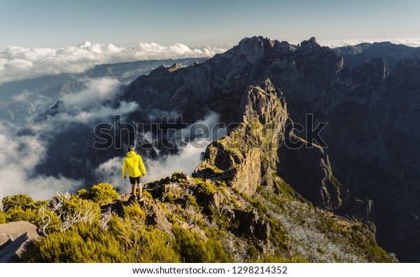 \
Man\
stands alone on the peak of rock. Beautiful moment the miracle of\
nature. Colorful mist in valley. Man hike. Trekking from Pico do\
Arieiro to Pico Ruivo, Madeira island,\
Portugal