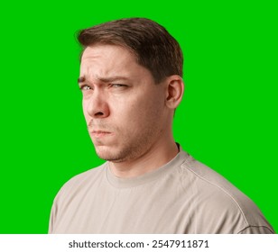 A man stands with arms crossed and a thoughtful expression in front of a green screen - Powered by Shutterstock