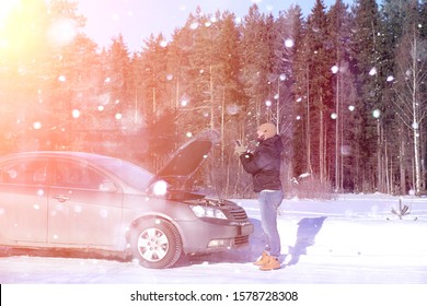 A Man Stands In Front Of A Broken Car In The Winter