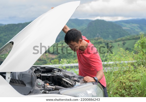 Man stands in front of car checking car condition\
after a broken car.