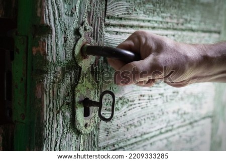 a man stands in front of an old door and a key with a lock hand