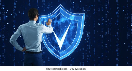 A man stands with his back facing the viewer, interacting with a digital shield icon with a check mark. The background is filled with binary code, symbolizing cybersecurity, data protection