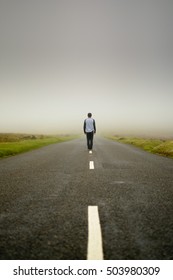 Man stands in the middle of an empty road in Dartmoor, England