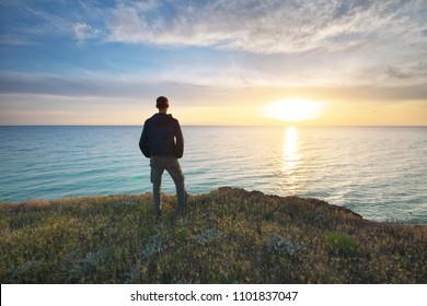 Man stands on the edge of the abyss and looks at the sea. Man relax on nature. 