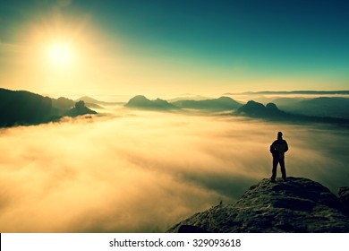 Man stands on the peak of sandstone rock in national park Saxony Switzerland and watching to Sun. Beautiful moment the miracle of nature