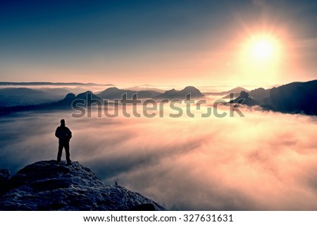 Man stands on the peak of sandstone rock in national park Saxony Switzerland and watching to Sun. Beautiful moment the miracle of nature. Misty valley. Man hike.Person silhouette stand.Foggy mountains