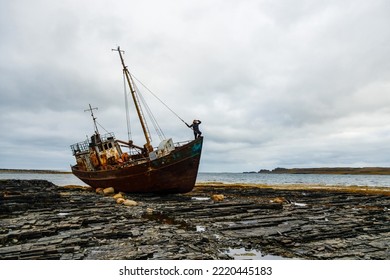 A Man Stands On The Prow Of An Abandoned Old Ship On The Coast Of The Arctic Ocean