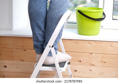 A Man Stands On A Stepladder And Washes The Window From Above. Feet On The Stairs. Cleaning, Repair.