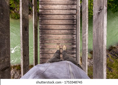 A man stands on a suspension wooden bridge in the mountains. Top view. - Powered by Shutterstock