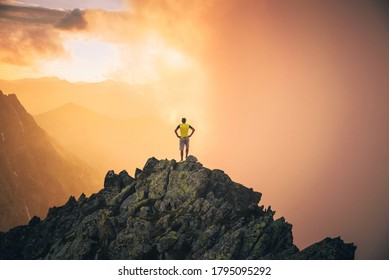 A man stands on top of a mountain, thinks and looks out into the valley at a beautiful sunset. landscape in orange colors. Adventure, hiking concept photo. Orange sky, edit space - Shutterstock ID 1795095292