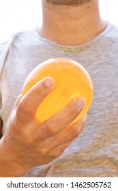 A Man Stands Outdoors And Holds A Plastic Water Bomb In His Hand - Playful Cooling In The Summer By A Balloon Full Of Water