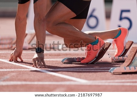 Man in a start block on an athletic track. A sprinter in a track and field race is poised at the starting line waiting for the start