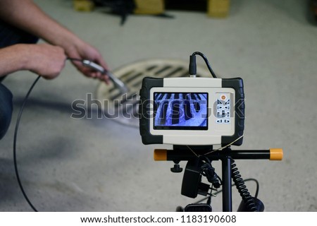 Man start using sewer inspection camera. Monitor showing picture from camera head that inspector is holding.