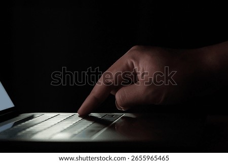 a man start working with laptop computer at the morning with sunshine backlight in a dark room with blank white screen shot with focusing on finger and keyboards and keep other part fo photo blurred
