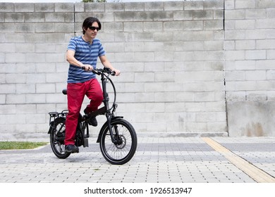 Man starting electric bike pedaling standing Striped shirt and red pants in medellin city