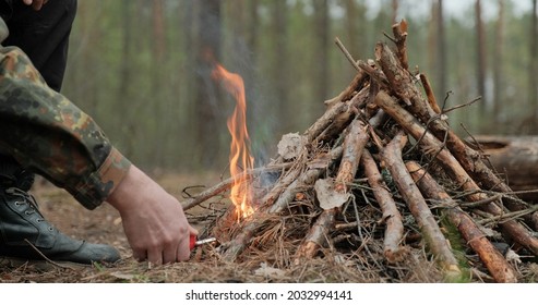 Man starts a fire in the forest using a lighter. Close-up of a man's hand lighting a fire with a lighter. Lighting a fire in the forest by a person. Low angle of a burning fire made of brushwood.	