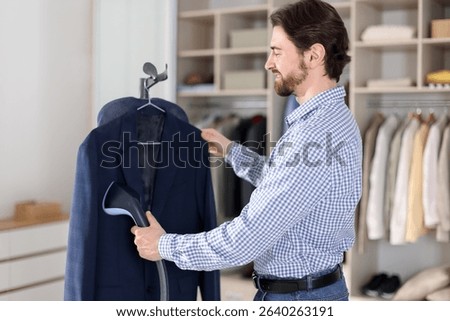 Man steaming jacket with stand steamer indoors