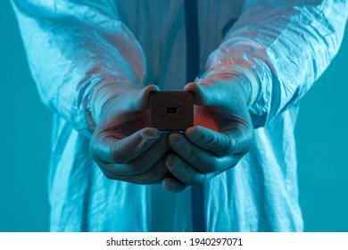 A man in sterile form holds a microprocessor, close-up. Microchip production technology, modern production, special microcircuit. Selective focus