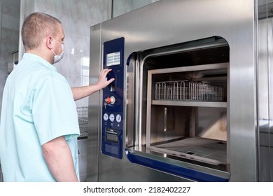 Man sterilising hospital material with a sterilisation machine - Shutterstock ID 2182402227