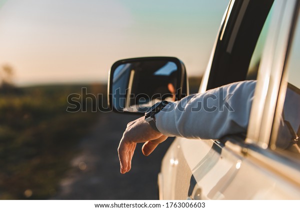 man stick out hand from car window. relaxed
enjoying at sunset