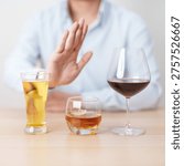 man stop hand gesture to refuse a glass of wine, beer, whiskey or cognac on table. say no to alcohol drink, stop alcoholism addiction, Responsibility, reject a drink before drive and quit booze