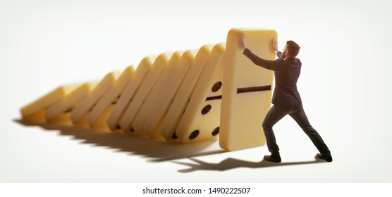 The man stops the falling dominoes. Concept of crisis management. - Shutterstock ID 1490222507