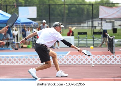 A Man Stretches Out To Hit A Pickleball Shot